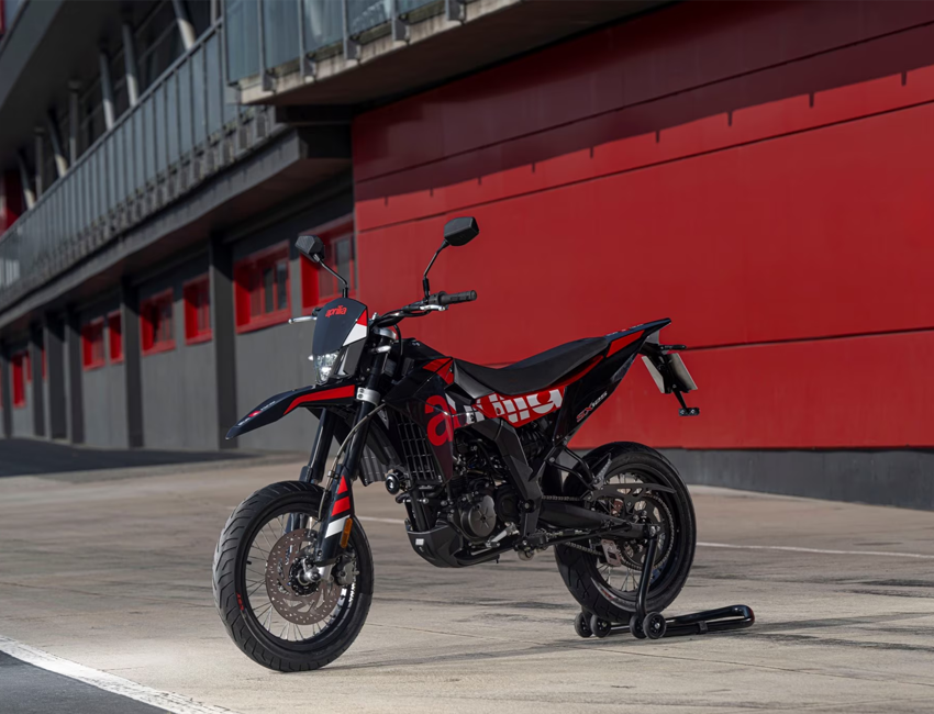 Vue latérale dynamique de l'Aprilia SX 125 sur route urbaine